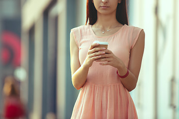 Image showing Beautiful woman holding paper coffee cup and enjoying the walk in the city