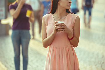 Image showing Beautiful woman holding paper coffee cup and enjoying the walk in the city