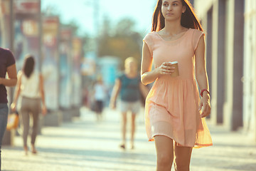 Image showing Beautiful woman holding paper coffee cup and enjoying the walk in the city