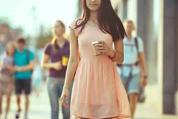 Image showing Beautiful woman holding paper coffee cup and enjoying the walk in the city