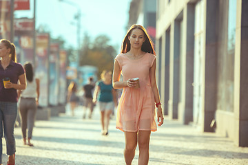 Image showing Beautiful woman holding paper coffee cup and enjoying the walk in the city