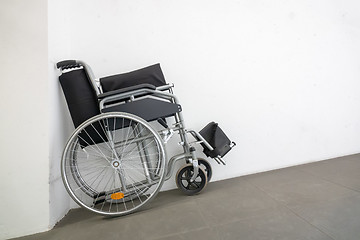 Image showing folded wheelchair at a white wall