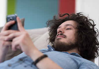 Image showing young man using a mobile phone  at home