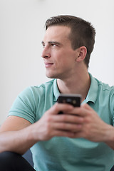 Image showing young man using a mobile phone  at home