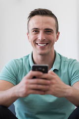 Image showing young man using a mobile phone  at home