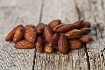 Image showing Pile of fresh organic almond seeds on rustick wooden table.