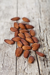 Image showing Pile of fresh organic almond seeds on rustick wooden table.