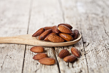 Image showing Organic fresh almond seeds on wooden spoon closeup on rustic woo