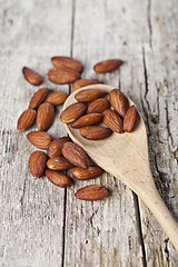 Image showing Fresh raw almond seeds on wooden spoon closeup on rustic wooden 