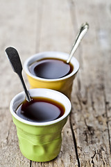 Image showing Green and yellow cups with black coffe and spoons on rustic wood