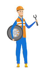 Image showing Young caucasian mechanic with tyre and spanner.