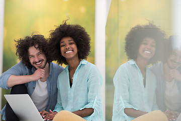 Image showing multiethnic couple using a laptop on the floor