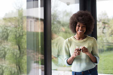 Image showing African American woman drinking coffee looking out the window