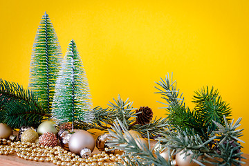 Image showing Christmas decoration glass balls with fir trees on yellow backgr