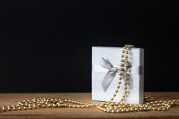 Image showing Holidays decoration gift box with golden perls on black backgrou