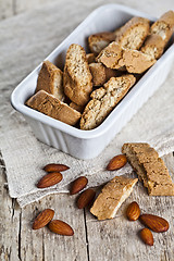 Image showing Cookies cantuccini in white ceramic bowl and almond seeds on lin