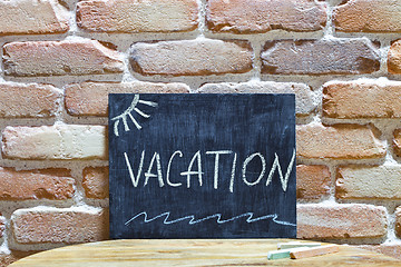 Image showing Chalk board with the word VACATION drown by hand and chalks on w