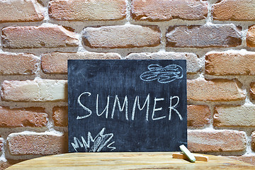 Image showing Chalk board with the word SUMMER drown by hand and chalks on woo