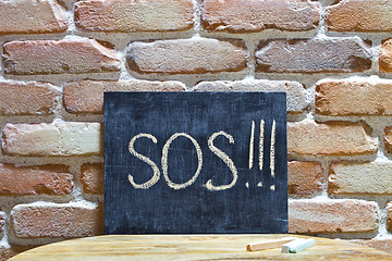 Image showing Chalk board with the word SOS! drown by hand and chalks on woode