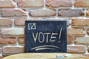Image showing Chalk board with the word VOTE! drown by hand and chalks on wood