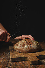 Image showing fresh organic bread cut a man\'s hands