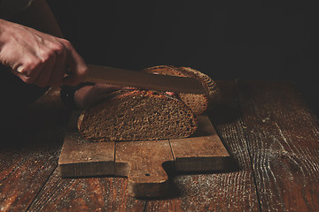 Image showing Hands cutting rye bread