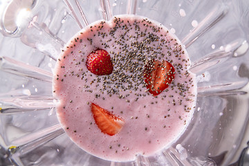 Image showing Preparation of milkshake from milk, strawberries and chia seeds in a bowl of a blender, top view