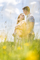 Image showing Young happy pregnant couple hugging in nature.