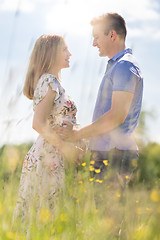 Image showing Young happy pregnant couple hugging in nature.