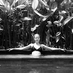 Image showing Sensual young woman relaxing in outdoor spa infinity swimming pool surrounded with lush tropical greenery of Ubud, Bali. Black and white image.