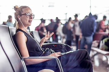 Image showing Female traveler talking on cell phone while waiting to board a plane at departure gates at asian airport terminal.