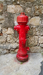 Image showing Red fireplug against a stone wall 