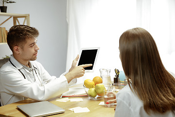 Image showing Smiling nutritionist showing a healthy diet plan to patient