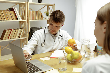 Image showing Smiling nutritionist showing a healthy diet plan to patient