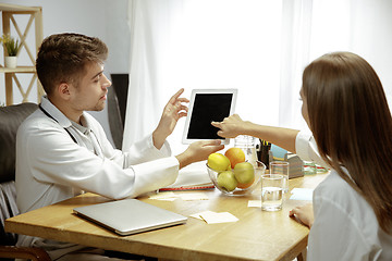 Image showing Smiling nutritionist showing a healthy diet plan to patient