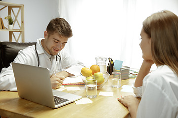 Image showing Smiling nutritionist showing a healthy diet plan to patient