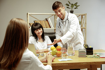 Image showing Smiling nutritionists showing a healthy diet plan to patient