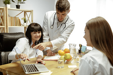Image showing Smiling nutritionists showing a healthy diet plan to patient