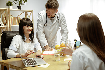 Image showing Smiling nutritionists showing a healthy diet plan to patient