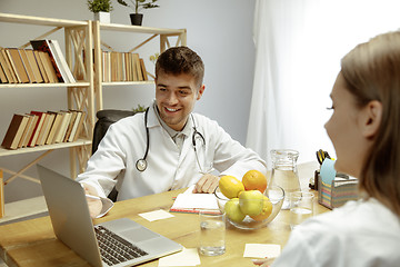 Image showing Smiling nutritionist showing a healthy diet plan to patient