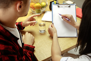 Image showing Smiling nutritionist showing a healthy diet plan to patient