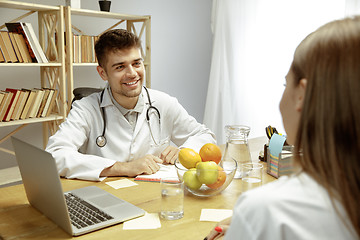 Image showing Smiling nutritionist showing a healthy diet plan to patient