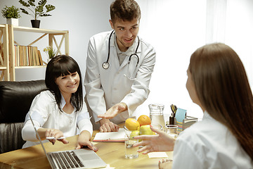 Image showing Smiling nutritionists showing a healthy diet plan to patient