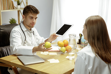 Image showing Smiling nutritionist showing a healthy diet plan to patient