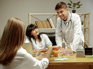 Image showing Smiling nutritionists showing a healthy diet plan to patient