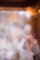 Image showing young mother and little cute daughter playing near the window