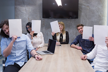 Image showing startup business team holding a white paper over face