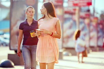 Image showing Beautiful girls holding paper coffee cup and enjoying the walk in the city