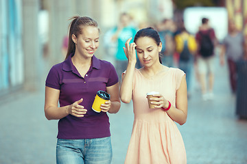 Image showing Beautiful girls holding paper coffee cup and enjoying the walk in the city