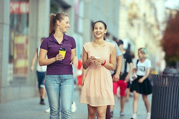 Image showing Beautiful girls holding paper coffee cup and enjoying the walk in the city